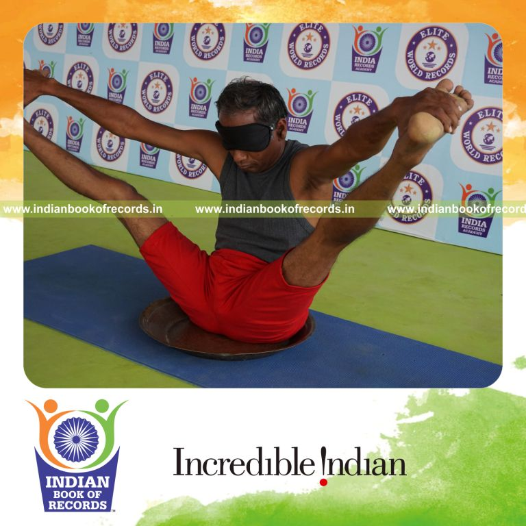individual holding kakasana yoga pose blindfolded on a brass plate for record in Indian Book of Records
