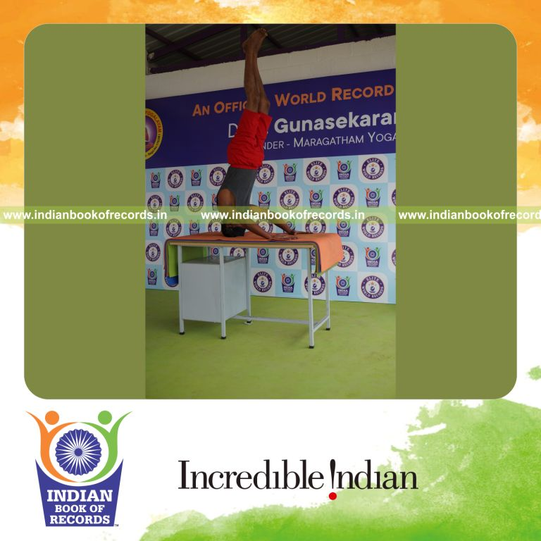 individual holding mukta sirsasana yoga pose blindfolded on a table for record in Indian Book of Records