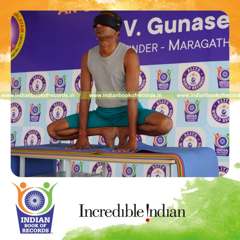 individual holding nagulasana yoga pose blindfolded on a table for record in Indian Book of Records