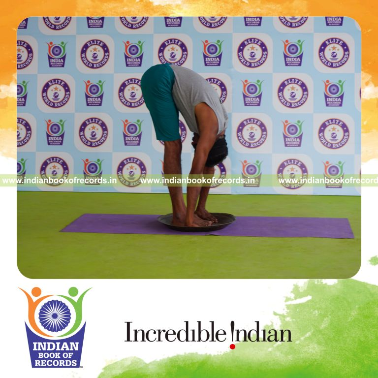 individual holding padahasthasana yoga pose blindfolded on a brass plate for record in Indian Book of Records