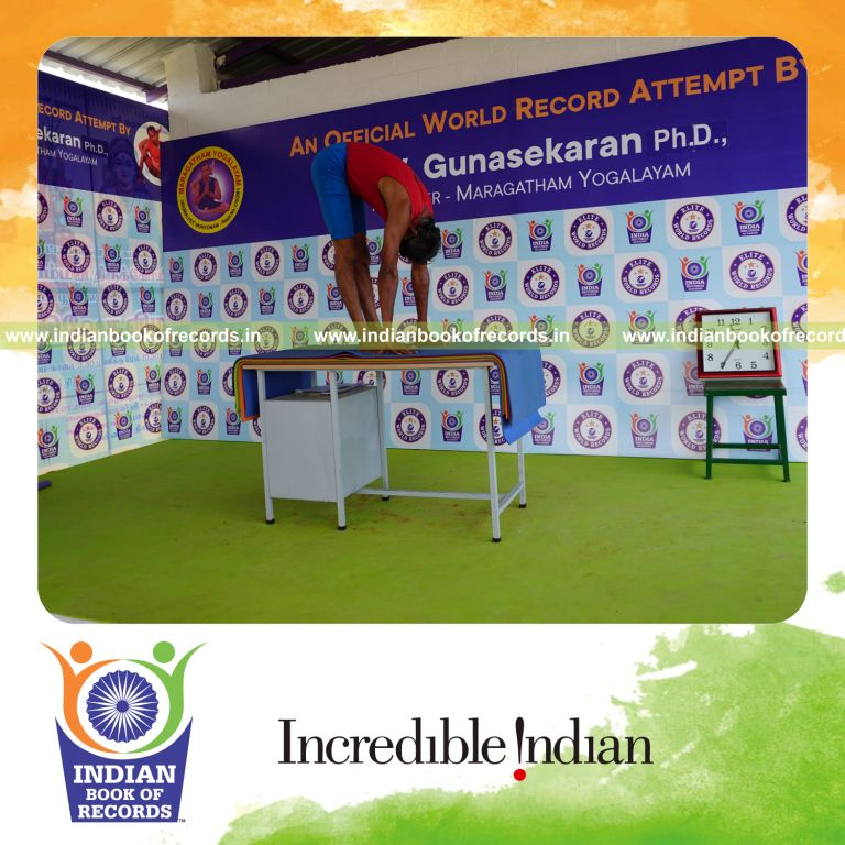 individual holding padahasthasana yoga pose blindfolded on a table for record in Indian Book of Records