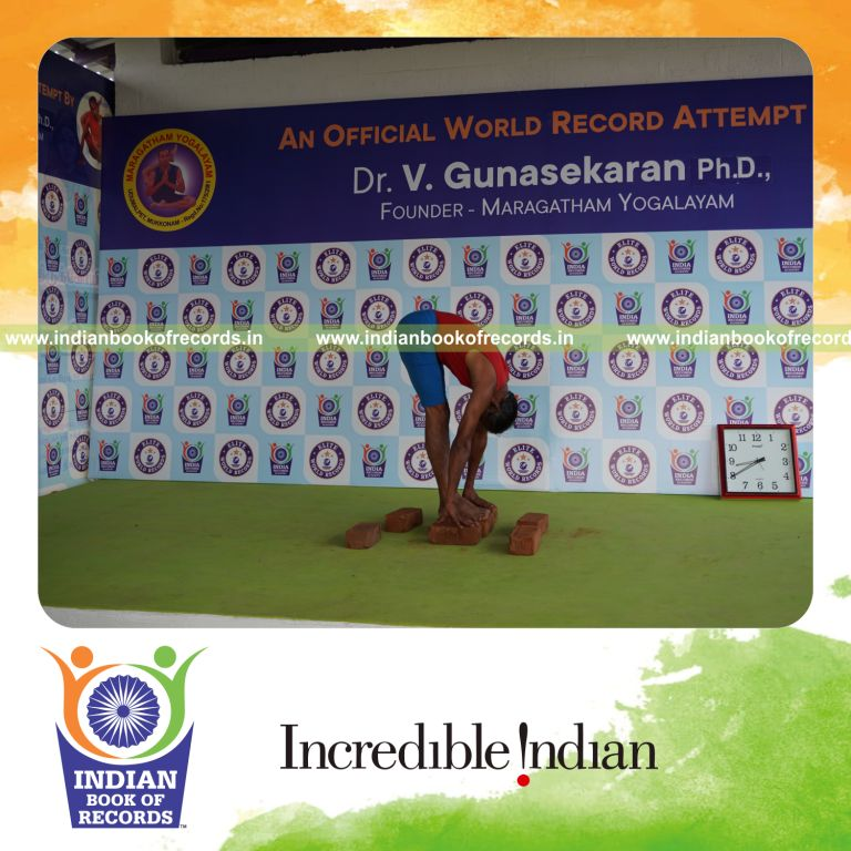 individual holding padahasthasana yoga pose on bricks for record in Indian Book of Records