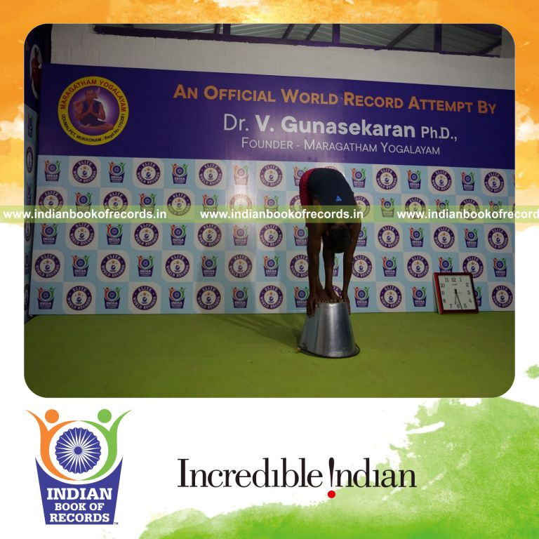 individual holding padahasthasana yoga pose on a bucket for record in Indian Book of Records