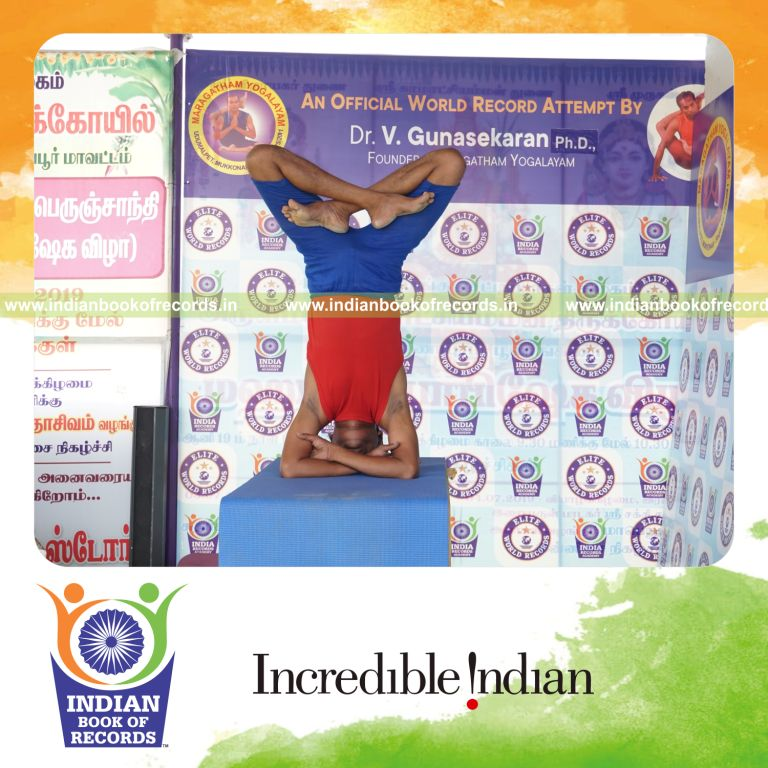 individual holding padma baddha hastha sirsasana yoga pose on a table for record in Indian Book of Records