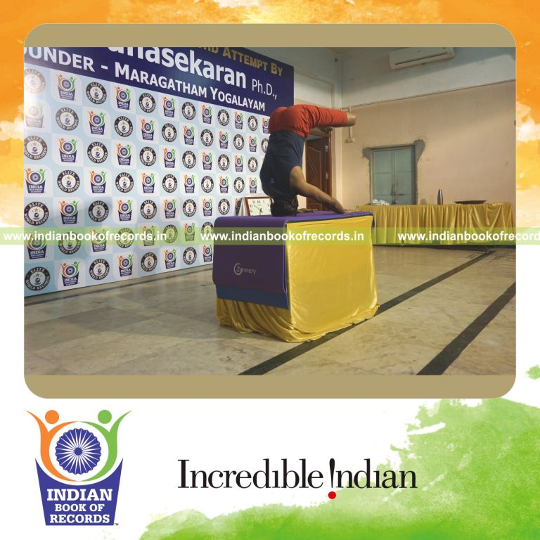 individual holding padma mukta sirsasana yoga pose blindfolded on a table for record in Indian Book of Records