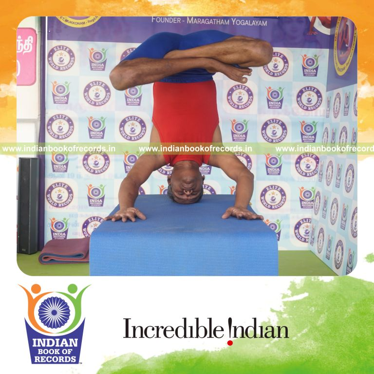individual holding padma mukta sirsasana yoga pose on a table for record in Indian Book of Records