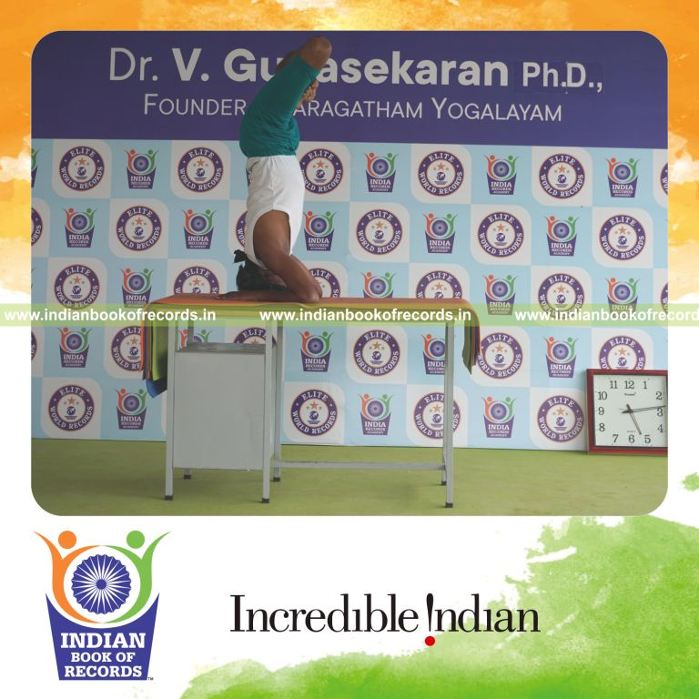 individual holding padma salamba sirsasana yoga pose blindfolded on a table for record in Indian Book of Records