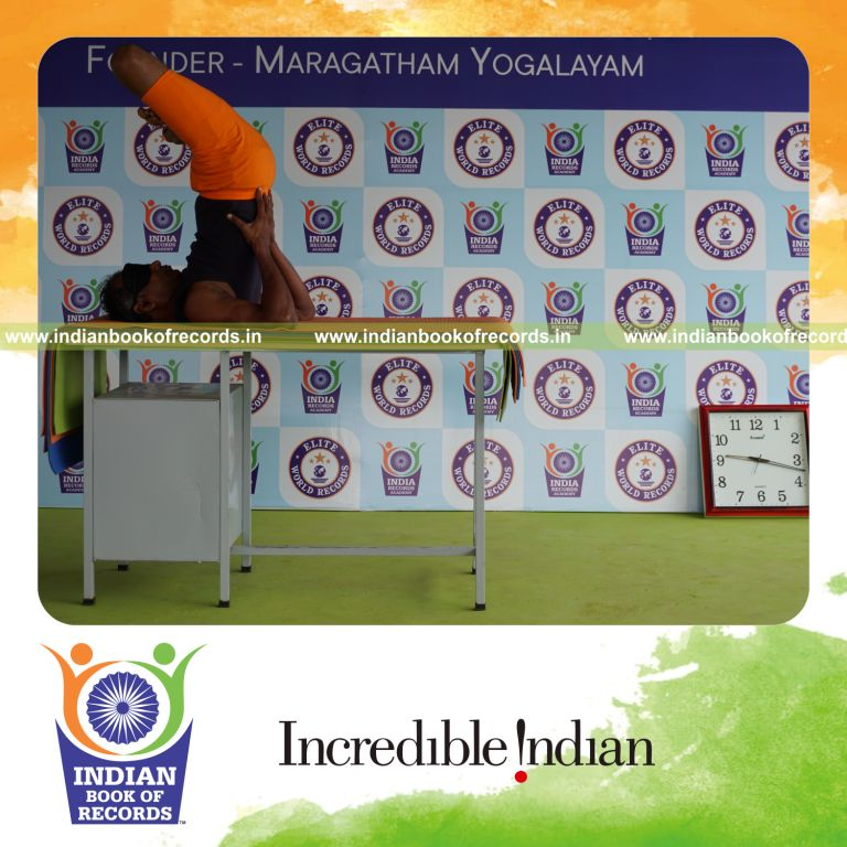 individual holding padma sarvangasana yoga pose blindfolded on a table for record in Indian Book of Records