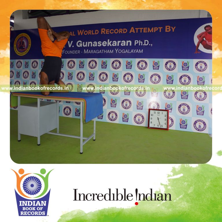 individual holding padma sirsasana yoga pose blindfolded on a table for record in Indian Book of Records