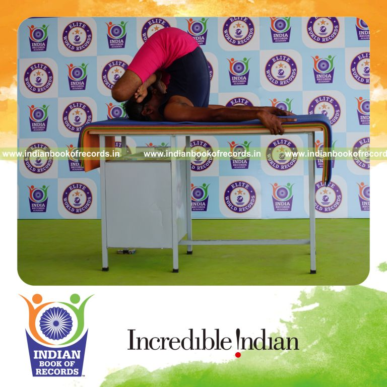 individual holding pindasana in salamba sarvangasana yoga pose blindfolded on a table for record in Indian Book of Records