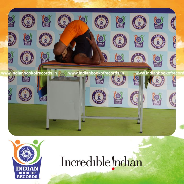 individual holding pindasana in sarvangasana yoga pose blindfolded on a table for record in Indian Book of Records
