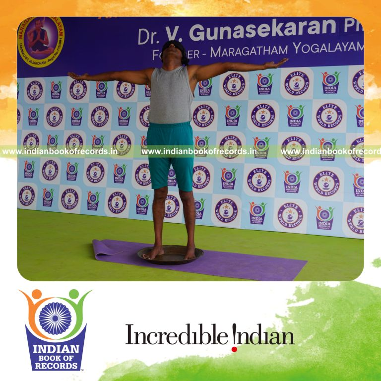 individual holding pirai chaturmukha trikonasana yoga pose blindfolded on a brass plate for record in Indian Book of Records