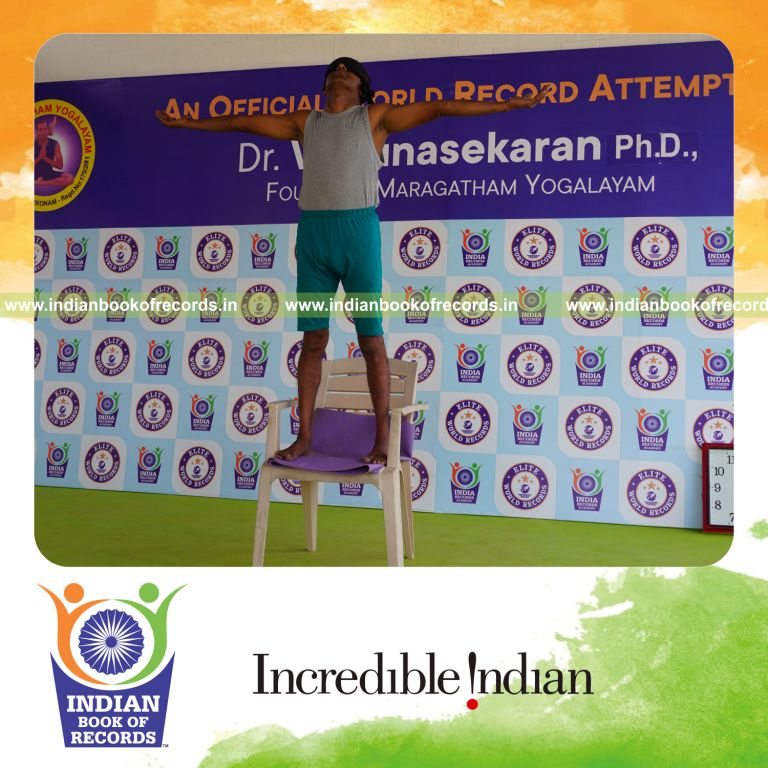 individual holding pirai chaturmukha trikonasana yoga pose blindfolded on a chair for record in Indian Book of Records