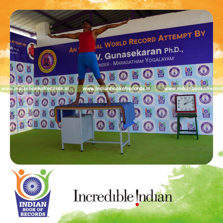 individual holding pirai chaturmukha trikonasana yoga pose blindfolded on a table for record in Indian Book of Records