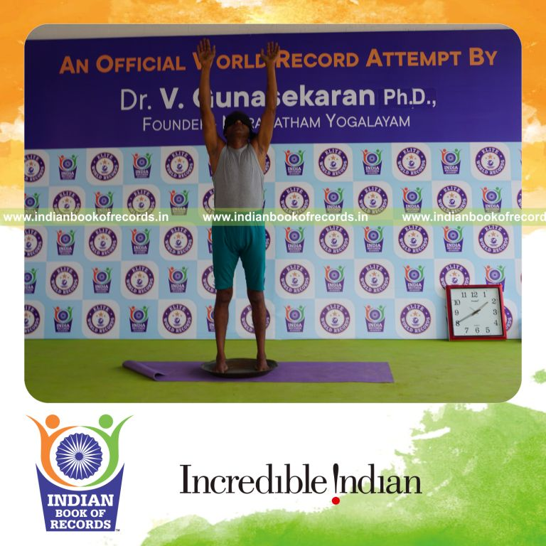 individual holding piraiasana yoga pose blindfolded on a brass plate for record in Indian Book of Records