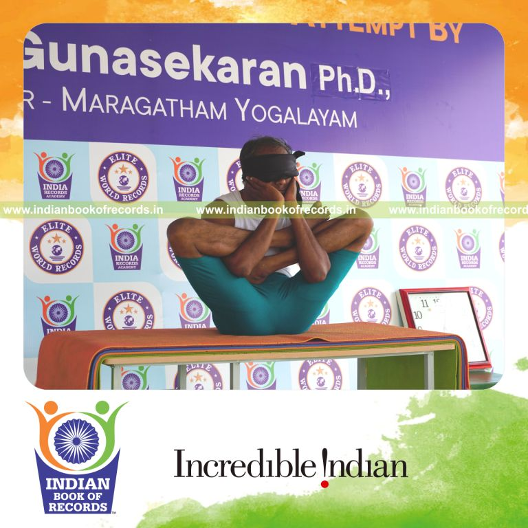 an individual holding purna garbha pindasana yoga pose blindfolded on a table continuously for the longest duration with control and balance for a record in Indian Book of Records