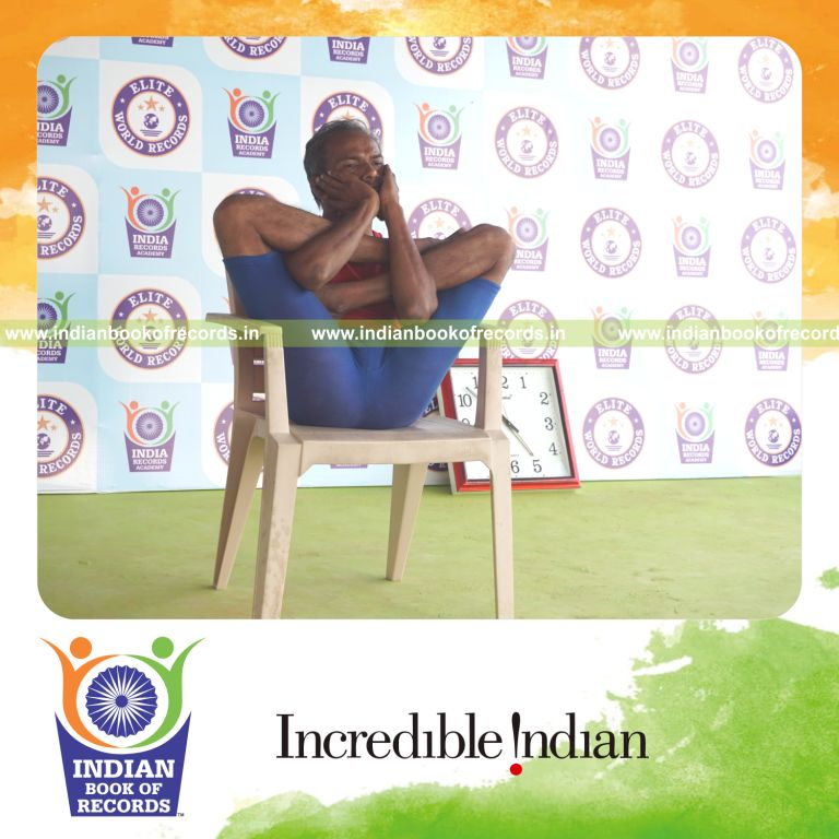 individual holding purna garbha pindasana yoga pose on a chair for record in Indian Book of Records