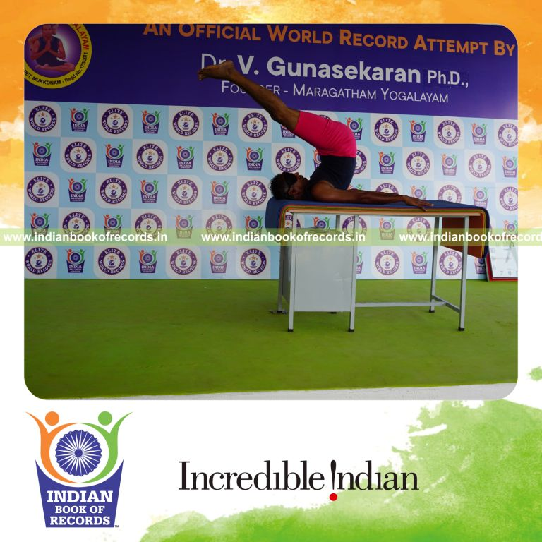 individual holding salamba sarvangasana yoga pose blindfolded on a table for record in Indian Book of Records