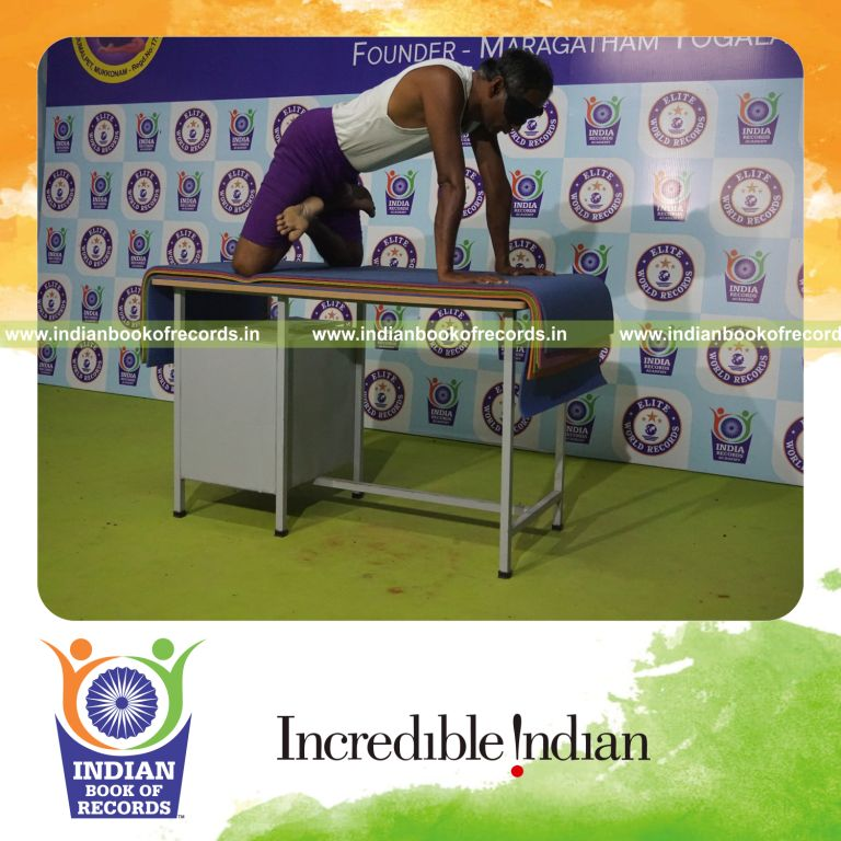 individual holding simhasana yoga pose blindfolded on a table for record in Indian Book of Records