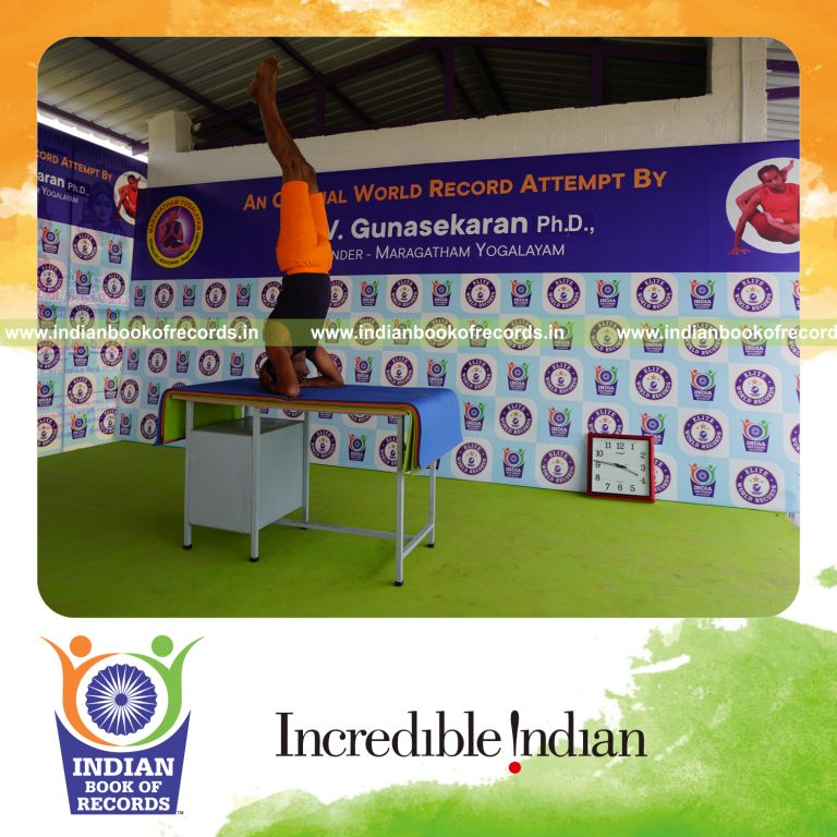 individual holding sirasasana yoga pose blindfolded on a table for record in Indian Book of Records