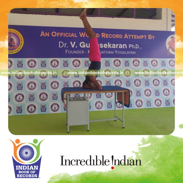 individual holding sirasasana yoga pose on a table for record in Indian Book of Records