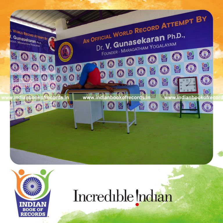 individual holding sivalingasana yoga pose blindfolded on a table for record in Indian Book of Records