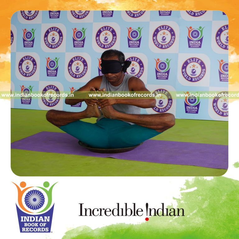 individual holding skandasana yoga pose blindfolded on a brass plate for record in Indian Book of Records