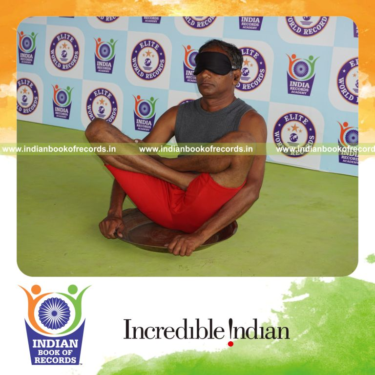 individual holding thulangasana yoga pose blindfolded on a brass plate for record in Indian Book of Records