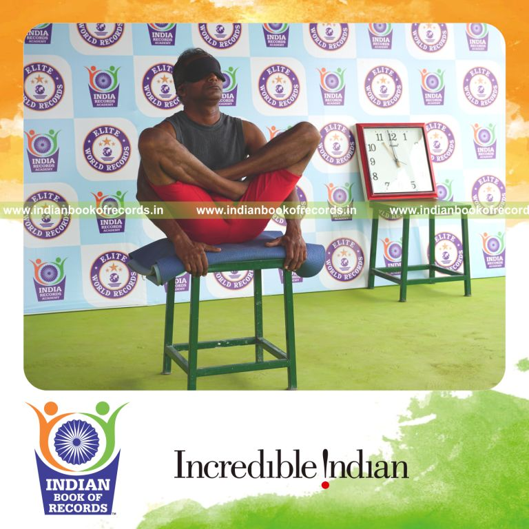 individual holding thulangasana yoga pose blindfolded on a stool for record in Indian Book of Records