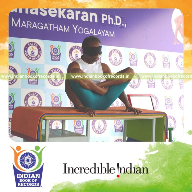 individual holding thulangasana yoga pose blindfolded on a table for record in Indian Book of Records