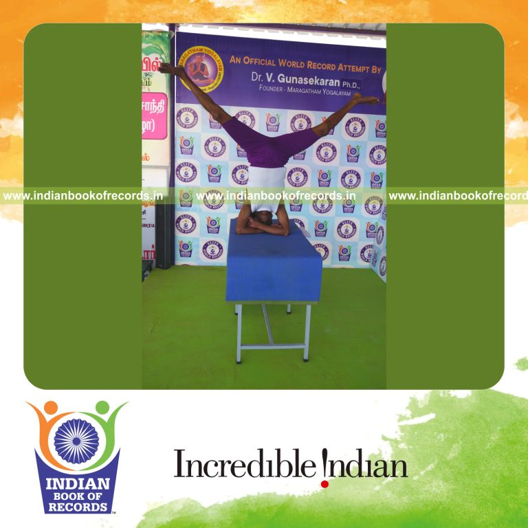 individual holding upavistha baddha hastha sirsasana yoga pose blindfolded on a table for record in Indian Book of Records