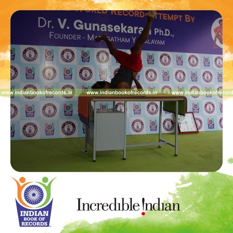 individual holding upavistha sarvangasana yoga pose blindfolded on a table for record in Indian Book of Records
