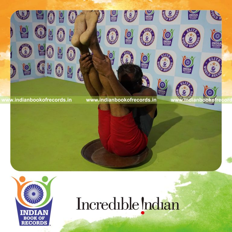 individual holding urdhva mukha paschimottanasana yoga pose blindfolded on a brass plate for record in Indian Book of Records