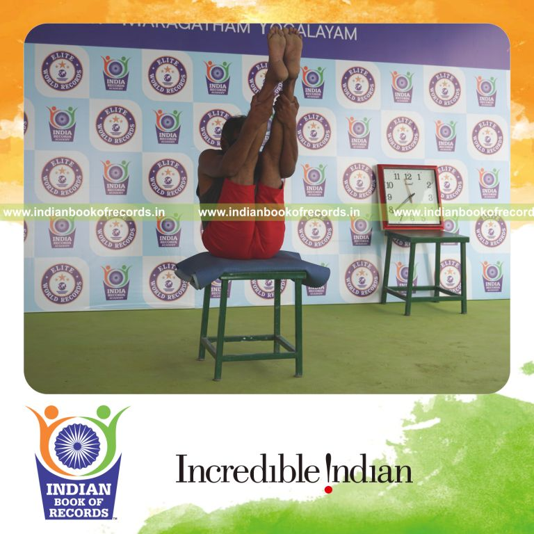 individual holding urdhva mukha paschimottanasana yoga pose blindfolded on a stool for record in Indian Book of Records