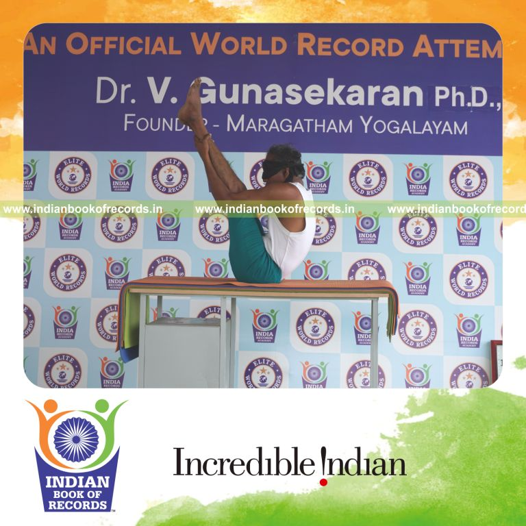 an individual holding urdhva mukha paschimottanasana yoga pose blindfolded on a table continuously for the longest duration with stability and control for a record in Indian Book of Records