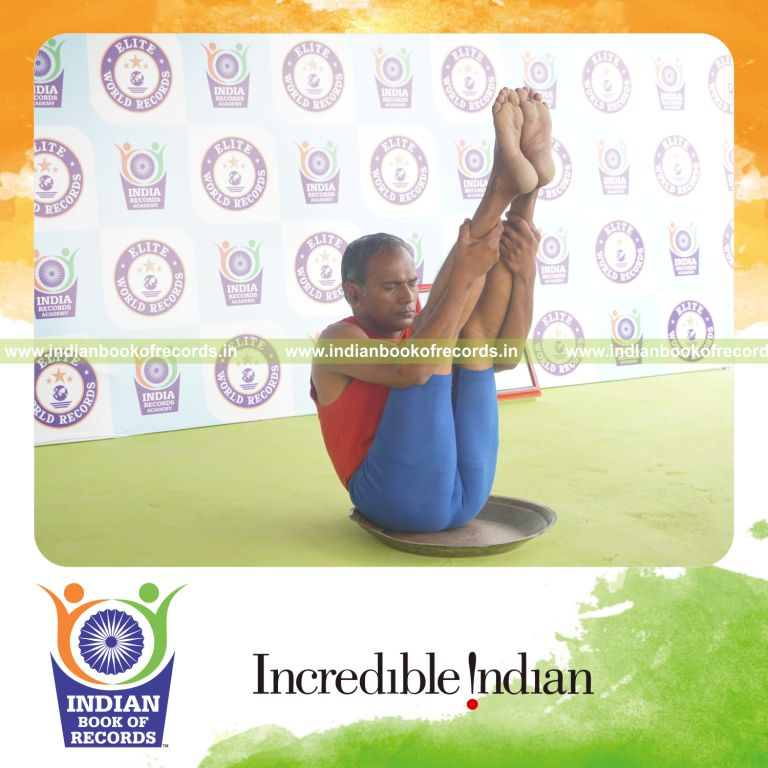 individual holding urdhva mukha paschimottanasana yoga pose on a brass plate for record in Indian Book of Records