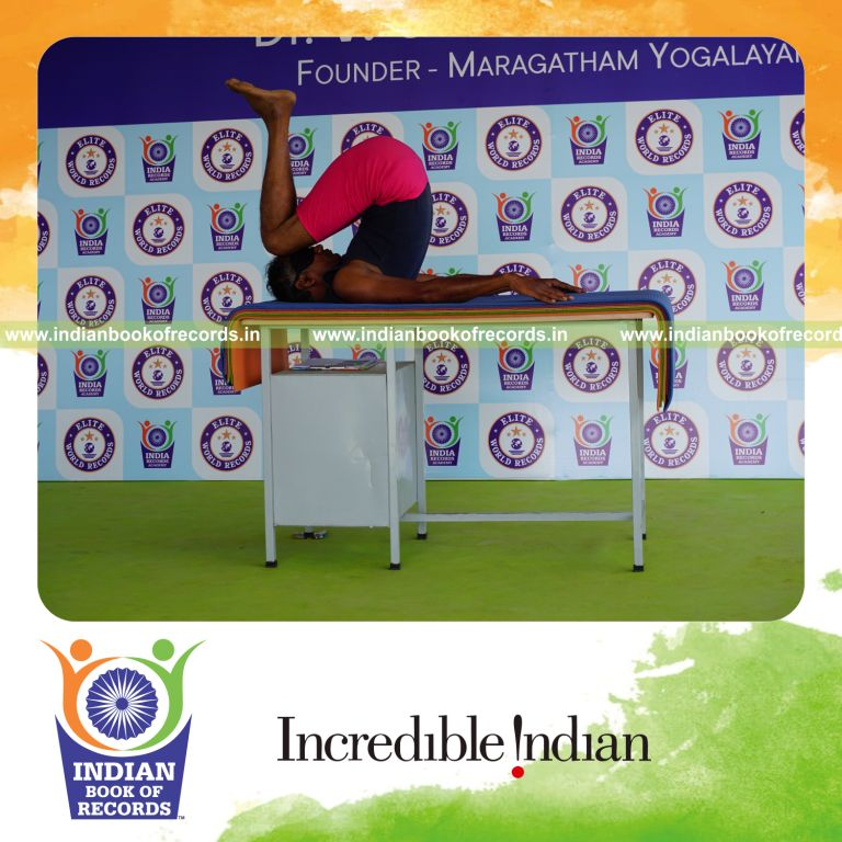 individual holding urdhva salamba sarvangasana yoga pose blindfolded on a table for record in Indian Book of Records