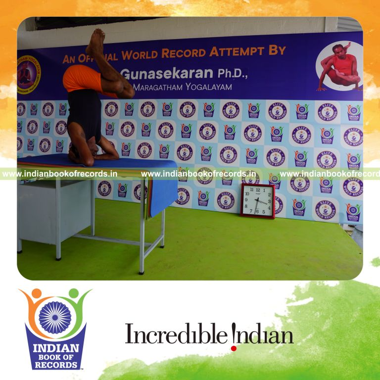 individual holding urdhva sirsasana yoga pose blindfolded on a table for record in Indian Book of Records