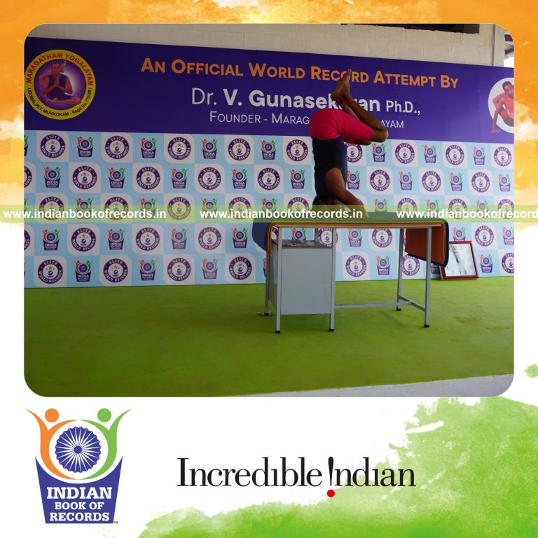 individual holding urdhva sirsasana yoga pose on a table for record in Indian Book of Records