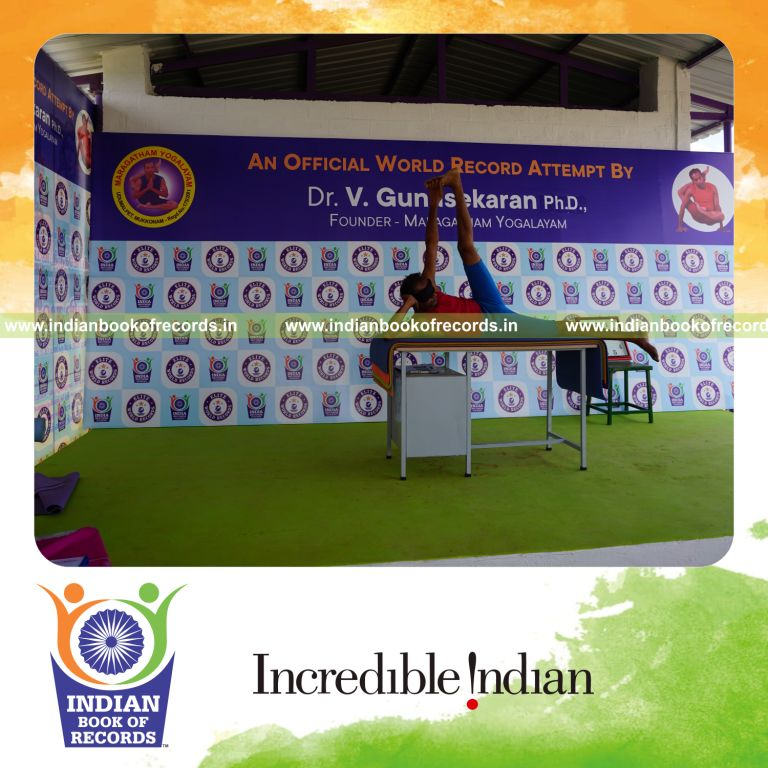 individual holding vama anandasana yoga pose blindfolded on a table for record in Indian Book of Records