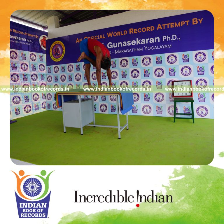 individual holding vama ardha baddha padmottasana yoga pose blindfolded on a table for record in Indian Book of Records