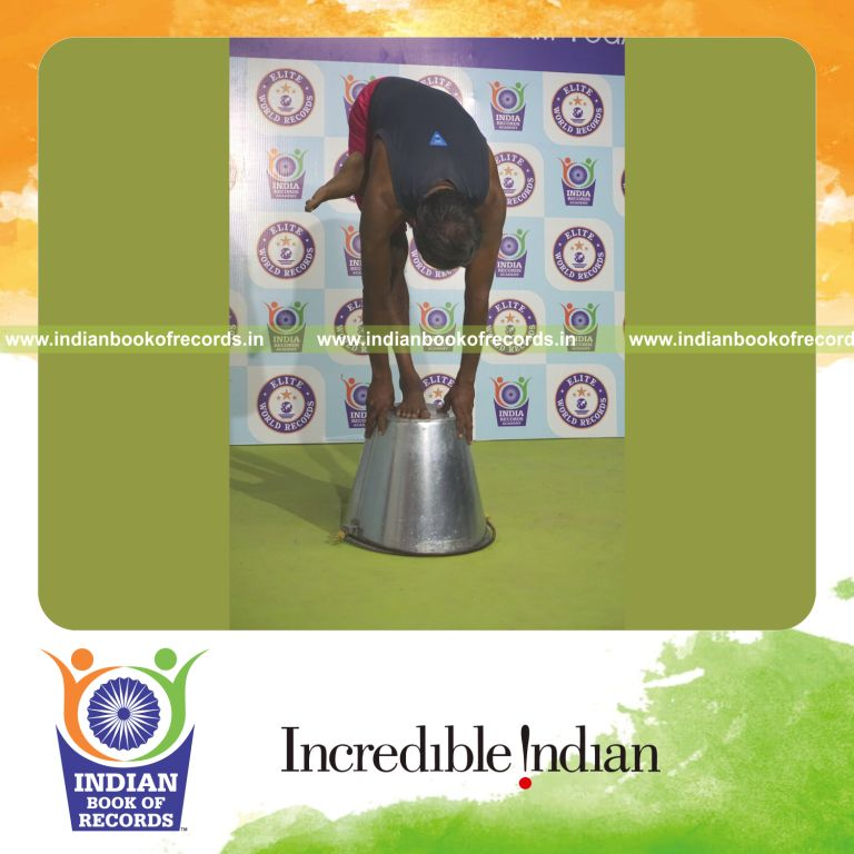 individual holding vama ardha baddha padmottasana yoga pose on a bucket for record in Indian Book of Records