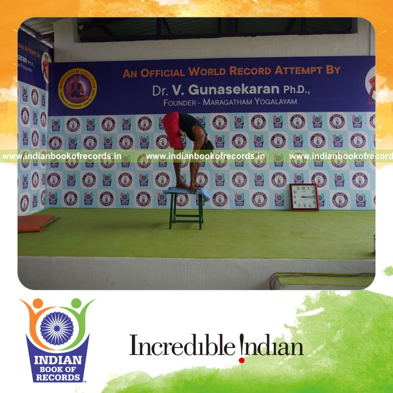 individual holding vama ardha baddha padmottasana yoga pose on a stool for record in Indian Book of Records