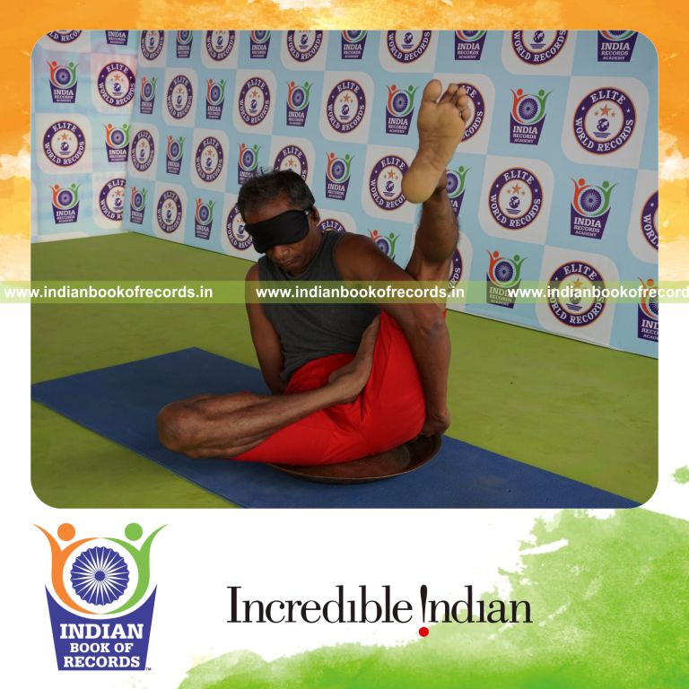 individual holding vama ardha baddha parsva krounchasana yoga pose blindfolded on a brass plate for record in Indian Book of Records