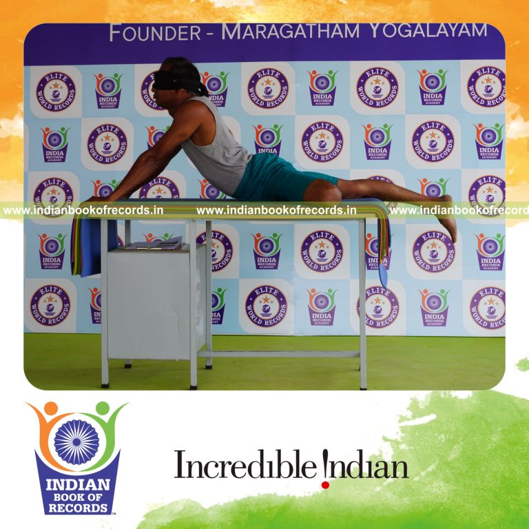 individual holding vama ardha bhujangasana yoga pose blindfolded on a table for record in Indian Book of Records