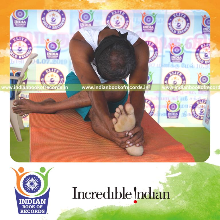 an individual holding vama ardha janu sirsasana yoga pose blindfolded on a table continuously for the longest duration with stability and control for a record in Indian Book of Records
