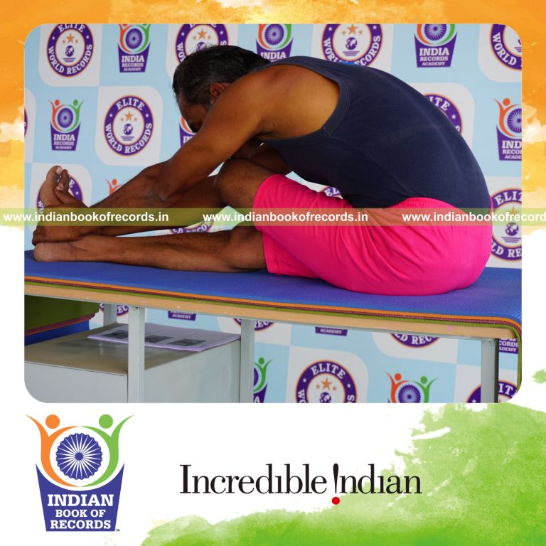an individual holding vama ardha janu sirsasana yoga pose on a table for the longest duration with balance and flexibility for a record in Indian Book of Records