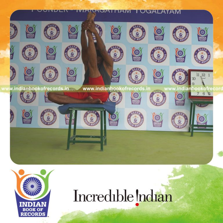 individual holding vama ardha krounchasana yoga pose blindfolded on a stool for record in Indian Book of Records