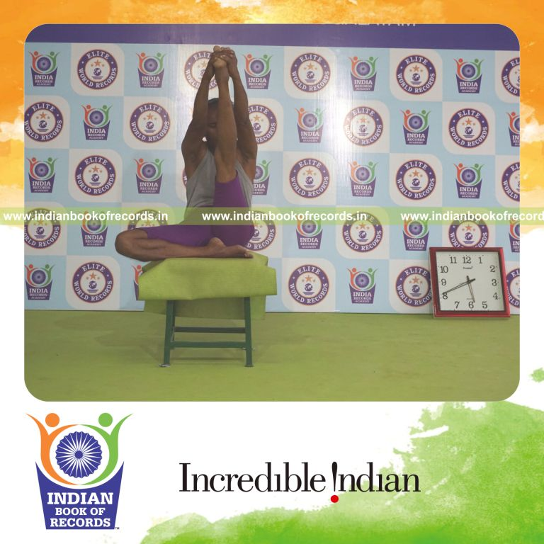 individual holding vama ardha krounchasana yoga pose on a stool for record in Indian Book of Records