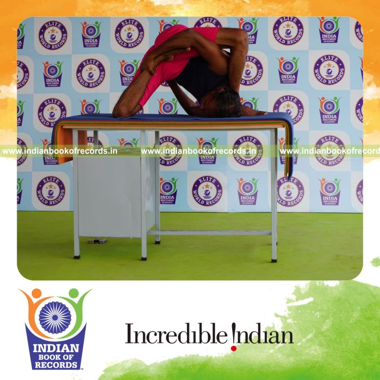 individual holding vama ardha padma astavakrasana yoga pose on a table for record in Indian Book of Records